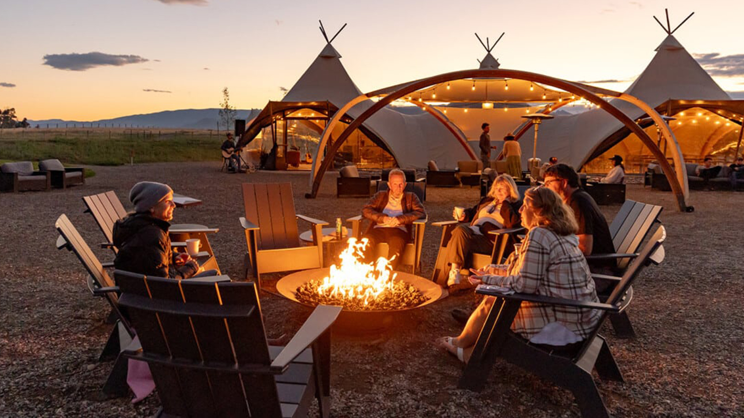 Under Canvas guests gather around the campfire, enjoying the camaraderie.