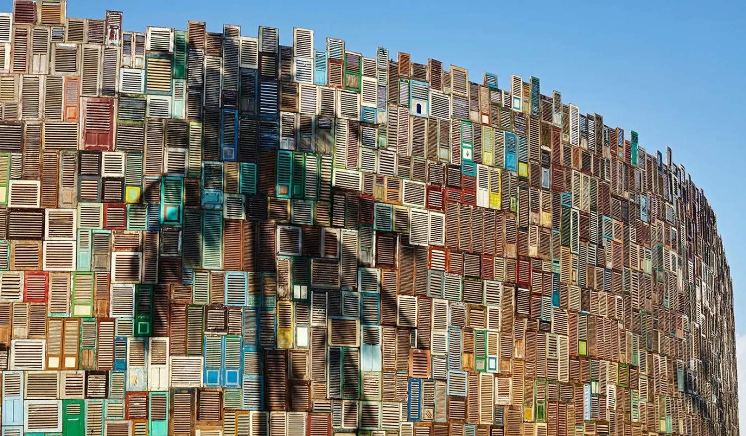 A unique display of a wall made from stacks of repurposed wooden windows.