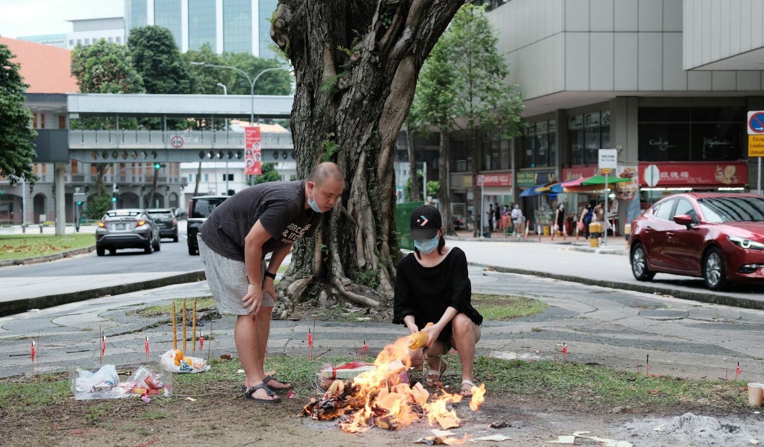 Two people burning offerings near a tree in Singapore. (Credit: Galen Crout)